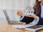 A real estate agent holding a wooden toy house.
