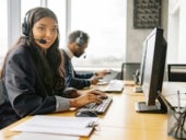 A smiling woman working in a call center while looking at camera.