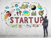 Businessman painting business startup imagery and text on a wall.